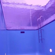 an empty swimming pool with blue water and ladders to the side, in front of a skylight