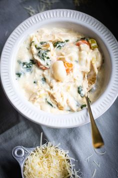 a white bowl filled with pasta and cheese next to a spoon on top of a table