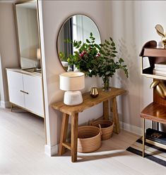 a living room with a table, mirror and plant