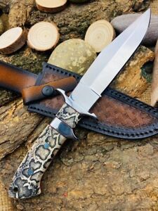 a knife with a snake skin handle on top of a wooden table next to wood slices