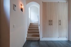 an entry way with stairs leading up to the door and light wood paneling on the walls