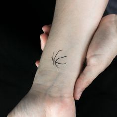 two hands holding each other with a small tattoo on the wrist that has an arrow in it