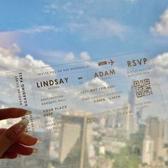 someone is holding up two tickets in front of a window with the city skyline behind them