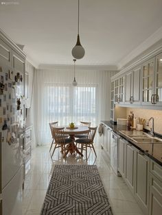 a kitchen filled with lots of white cabinets and counter top space next to a dining room table