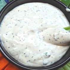 a black bowl filled with white sauce on top of carrots and celery