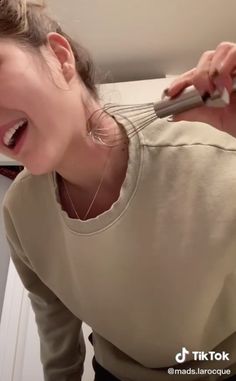 a woman is brushing her teeth with an electric toothbrush while standing in the bathroom