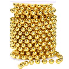 a spool of gold colored beads on a white background