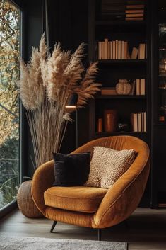 an orange chair sitting in front of a book shelf filled with lots of books and plants