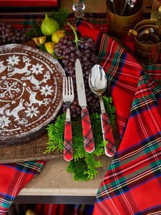 a table topped with a pie covered in frosting next to silverware and fruit