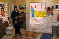 a man and woman standing in front of a shower curtain with the names of each element on it