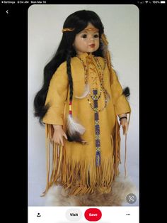 a doll with long black hair wearing a yellow outfit and feathers on it's head