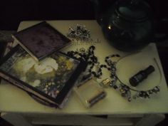 a table topped with pictures and jewelry on top of a white table next to a tea pot