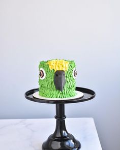 a cake with green icing and yellow flowers on it sitting on a black stand