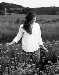 black and white photograph of a woman walking through a field with wildflowers in the foreground