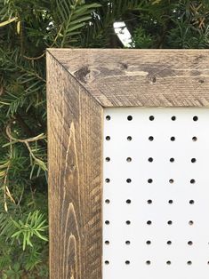 a wooden frame with holes in it sitting on top of a green tree covered ground