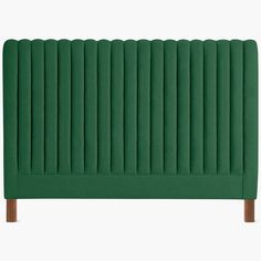 an upholstered green headboard with wooden legs