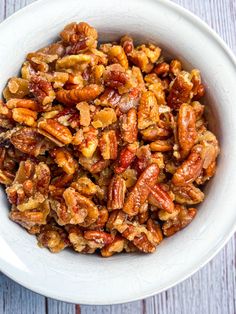 a white bowl filled with nuts on top of a wooden table