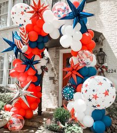 an american flag balloon arch with red, white and blue balloons in front of a house