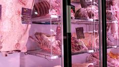 meat is displayed in a display case at a butcher's shop with purple lighting