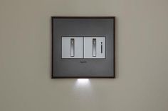 the light switch has two lights on each side of it and is mounted to the wall