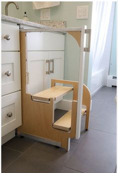 an open cabinet door in a kitchen next to a sink and counter top with drawers