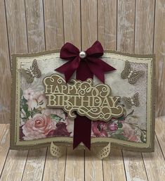 a happy birthday card with flowers and butterflies on the front, tied in a red ribbon