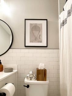 a white toilet sitting in a bathroom next to a sink and shower head mounted on a wall