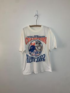 Celebrate a historic win with this 1993 Toronto Blue Jays World Series Championship Starter T-Shirt! Featuring bold graphics commemorating the Blue Jays' championship victory, this vintage tee is a must-have for any baseball fan. Made from high-quality cotton for a comfortable fit, it's perfect for reliving the excitement of the 1993 season and showcasing your team pride. Awesome condition. Missing size tag but fits like a L. Width : 22" Length : 28" Baseball Fan, Baseball Shirt, Vintage Baseball, Toronto Blue Jays, Fashion Board, Bold Graphics, Blue Jays, Vintage Tee, Baseball Shirts