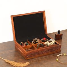 an open wooden box with jewelry inside sitting on a table next to a necklace and bracelet holder