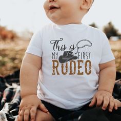 a baby wearing a shirt that says, this is my first rodeo