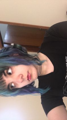 a woman with blue and green hair is posing for the camera