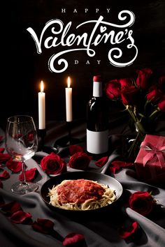 a plate with spaghetti and sauce on it next to two wine glasses, candles and roses