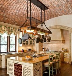 a kitchen with an island and pots hanging from the ceiling