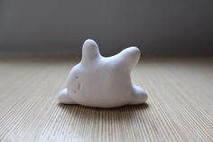 a small white rabbit figurine sitting on top of a wooden table