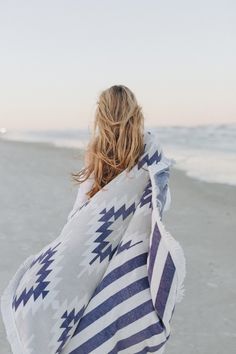 a woman wrapped in a blanket on the beach