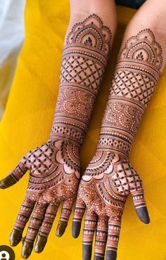 two hands with henna tattoos on them, one is showing off the intricate design