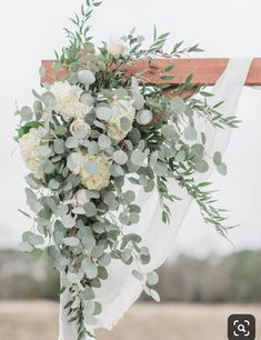 a wedding arch decorated with greenery and white flowers