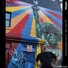 a man standing in front of a building with a mural on it's side