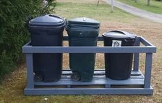 three trash cans sitting on top of a wooden pallet