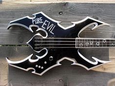 a black and white electric guitar with graffiti on it's body is mounted to a wooden fence