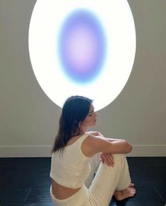 a woman sitting on the floor in front of a large white ball with blue circles