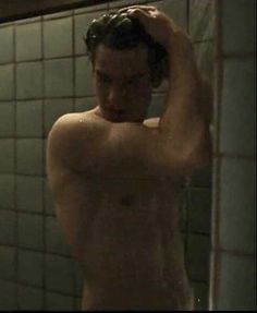 a shirtless man standing in front of a shower with his hands on his head