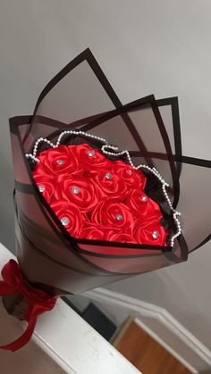 a heart shaped box with roses in the center and pearls on the bottom, hanging from a ceiling