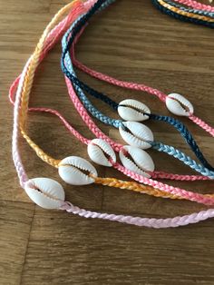 several seashells and braided cord necklaces on a wooden table