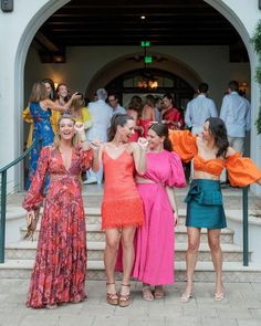 three women in dresses standing on steps with their arms around each other