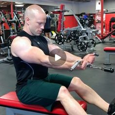 a man sitting on top of a red bench in a gym holding a barbell