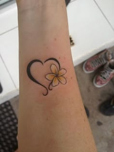 a heart shaped tattoo with a flower on the side of its arm and a clover in the middle