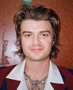 a close up of a person wearing a shirt and tie with a necklace on his neck