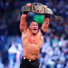 a man holding up a wrestling belt in the air with his hands above his head