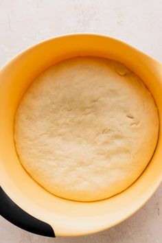 a yellow bowl filled with dough on top of a table